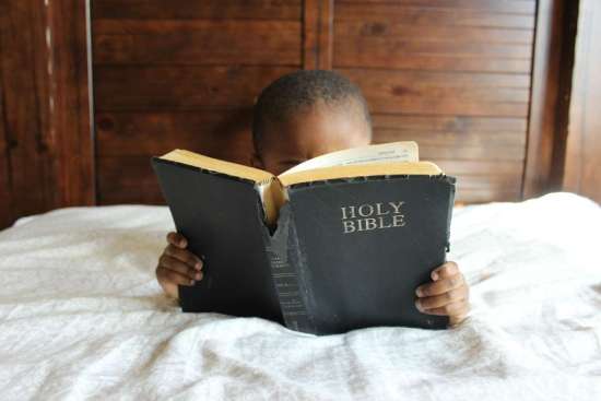 A child reading her bible as a source of light in this dark world.