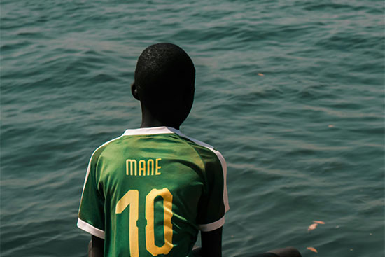 African teen wearing Mane jersey Sadio Mane is a n example of how humble beginnings can lead to extraordinary accomplishments.