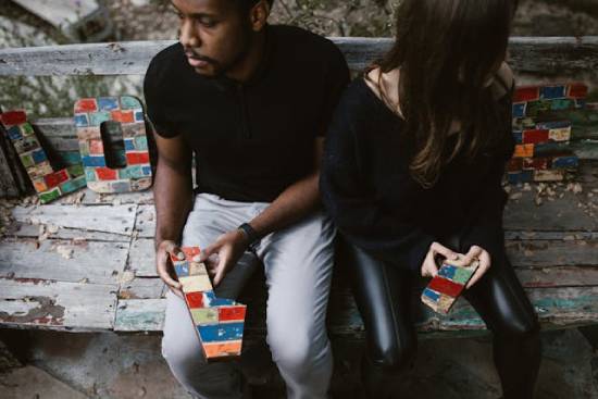 A couple sitting next to decor reading, 'love,' as they tear the letter 'v' apart.