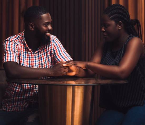 A husband and wife clasping hands as they stand and talk together.
