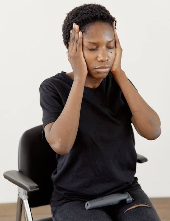A woman with her eyes closed, clutching her face in distress.