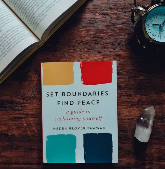 A self-help book on setting boundaries rests on top of a desk.