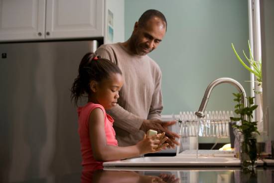A father teaching his young daughter to wash her hands
