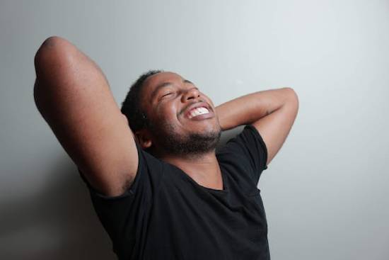 Happy Debt-Free Man Image A debt-free man smiling with his arms raised and his hands folded behind his head