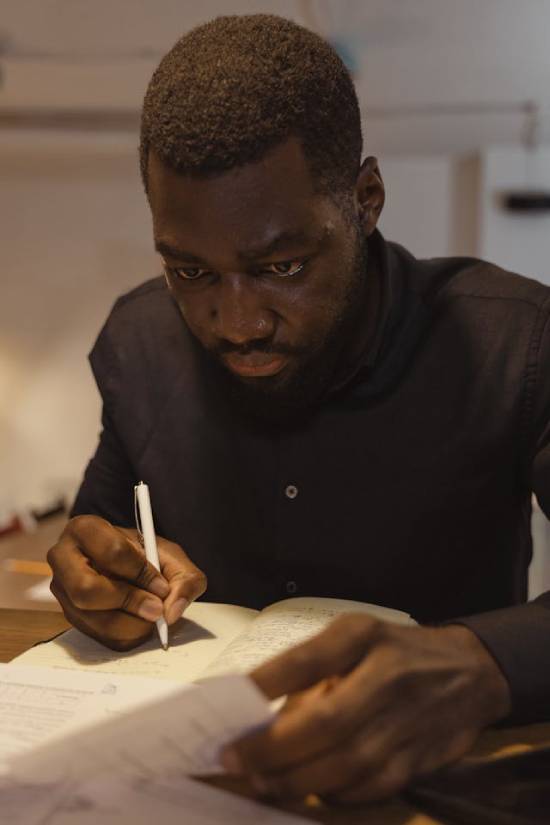 A Man Counting His Debt A man keeping track of his debt by writing it down in a journal