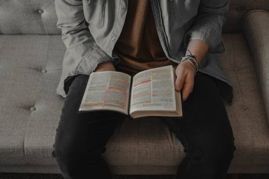 A Person Reading Highlighted Bible A man reading his marked Bible on a couch. Reading stories about others who faced discouragement can strengthen our faith.