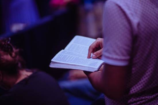 A person looking for verses in the Bible, highlighting the importance of going to God for answers.