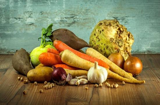 Garlic and Carot A pile of nutritious vegetables and nuts resting on a wooden table.