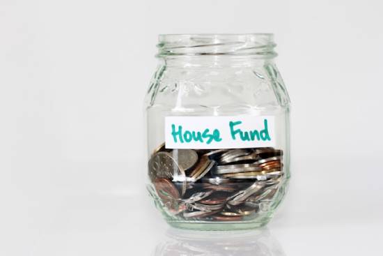 A glass home savings  jar geared towards a house fund.