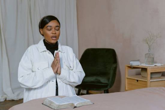 A Woman Praying with Her Bible A woman praying with her Bible open shows how people can claim God's promises by faith.