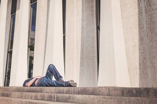 A Drained Man Lying Flat A drained and fatigued man lying flat on a pavement.