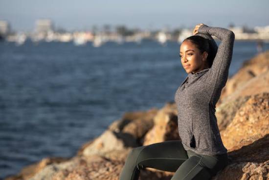 A Woman on Fitness Routine A health-conscious woman keeping up with her fitness routine by the seashore.