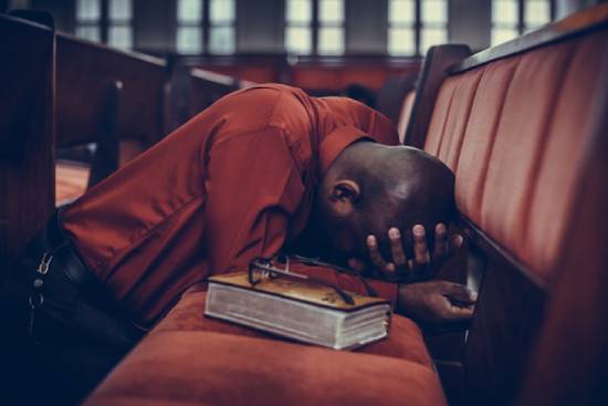 A man kneeling in prayer after studying Scriptures.