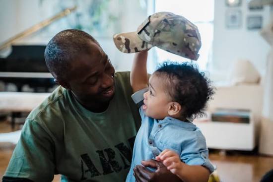Father Smiling at a Crying Baby Boy A father in a green army shirt smiling at a crying baby boy to calm him.
