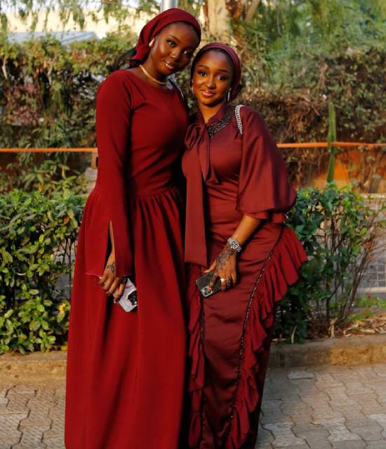 Two ladies in Elegant Maroon Dresses Two lady friends in elegant maroon dresses posing for a photoshoot.
