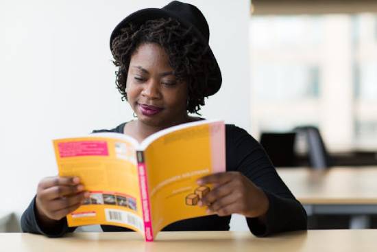 A Woman Reading a Book A woman in a black long-sleeved blouse reading a yellow-covered book to learn more about contentment and stewardship.