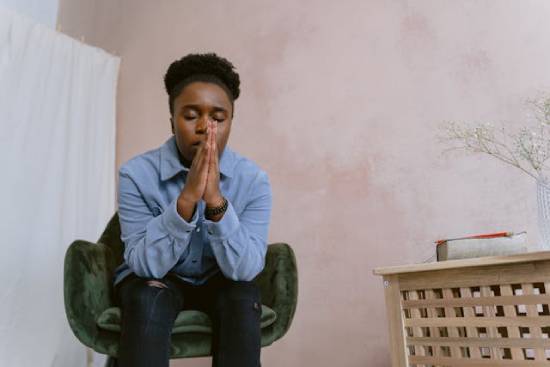 Woman Seeking God's Guidance Through Prayer An afro-haired woman sitting on a chair praying to God for clarity in some consequential decisions she needs to make