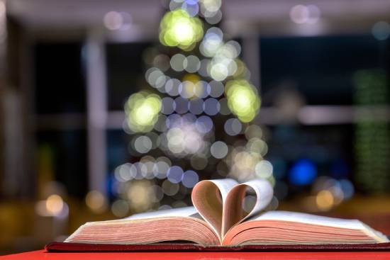 An open Bible with a two pages folden inro a heart shape.