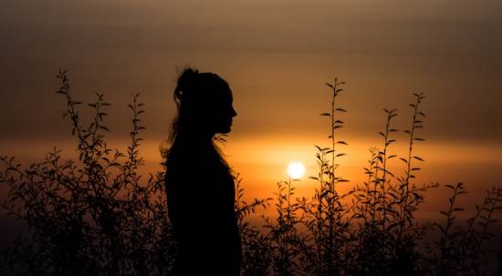 Silhouette of a Woman Meditating Silhoutte of a woman meditating on emotional healing at dusk.