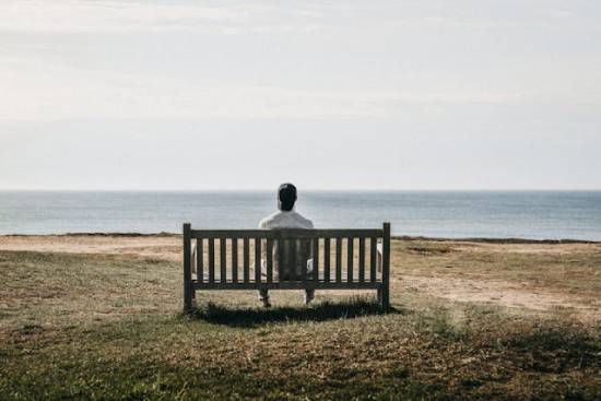 A single man sitting alone at the seashore.