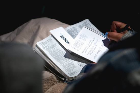 A person having a Bible study with a study plan and a notebook.
