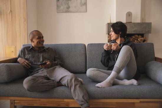 A couple having safe conversations at home on a couch.