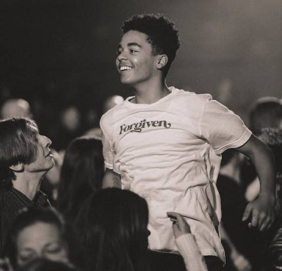 A happy youth celebrating God's forgiveness during a spiritual meeting.