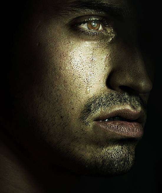 A solem face of a sad man in tears and deep thoughts.