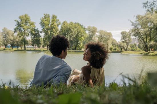 A young couple having safe conversations during a date by the lake.