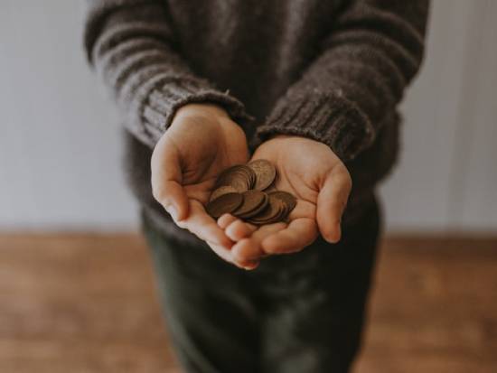 Hands of a man holding copper coins to be allocated to various budgetary needs.