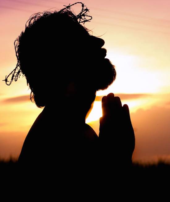 Silhouette of Jesus Christ in a crown of thorns kneeling in prayer.
