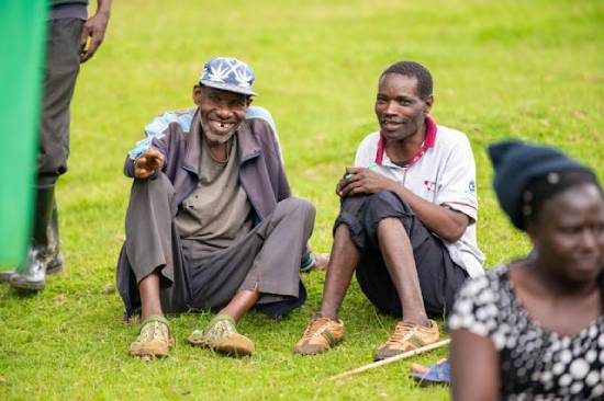 Two Men Talking Happily Two adult men smiling while having a talk on parenting, seated on a lawn.
