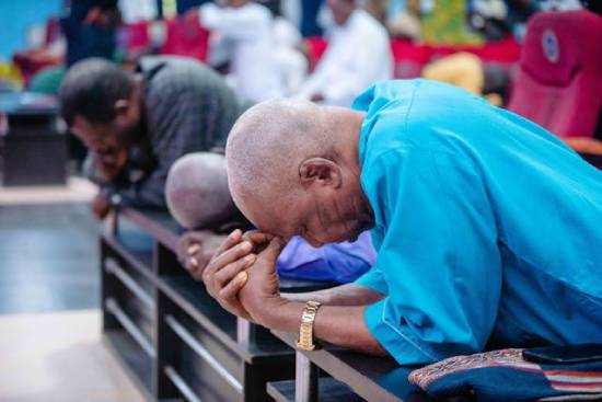 A group of people kneeling and praying in a church.