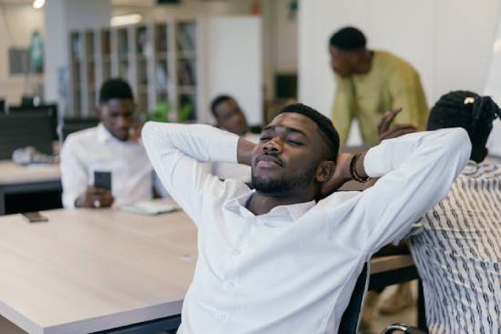 A man in a white long-sleeved shirt resting on a chair during working hours.