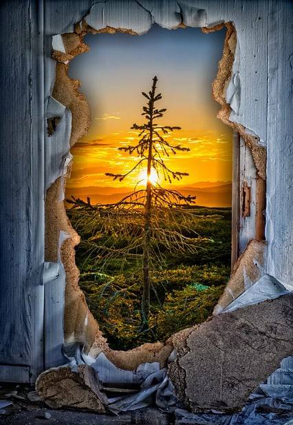 A wall cutout to a beautiful sunset symbolising hope.