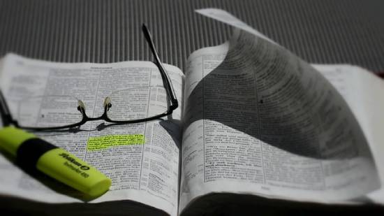 Bible Study Accessories An open Bible with a luminous green highlighter and spectacles placed in it.