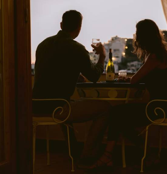 A couple taking liquor together in a pub at dusk.