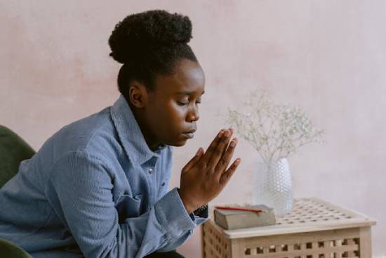 A woman in a blue long-sleeved shirt praying after studying the word of God.