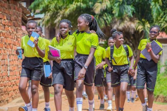 Students in School Uniform Students in luminous green polo-neck tops and black shorts carrying books as they walk to class.