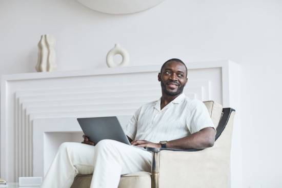 Work From Home A man in white long trauser and a short -sleeved shirt working on a laptop at home.