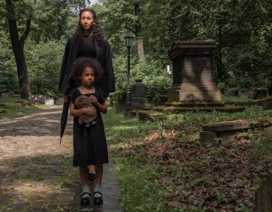 Woman and Little Girl in Cemetery A woman and a little girl walking in a cemetery dressed in black.