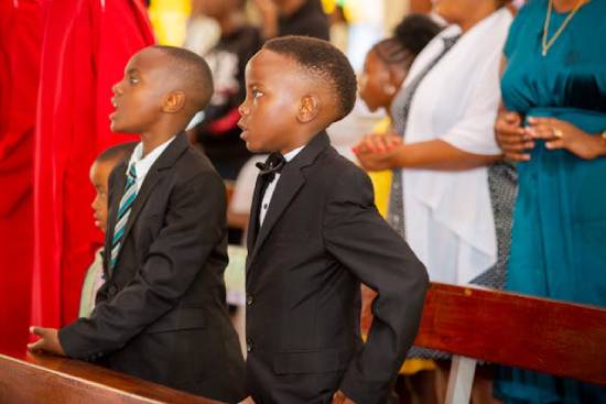 Two boys in elegant black suits attending a church service.