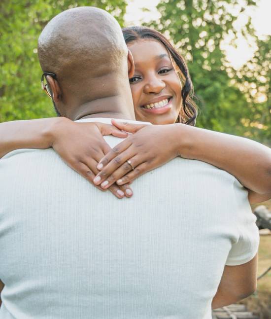 A happy loving couple hugging with the woman smiling broadly.