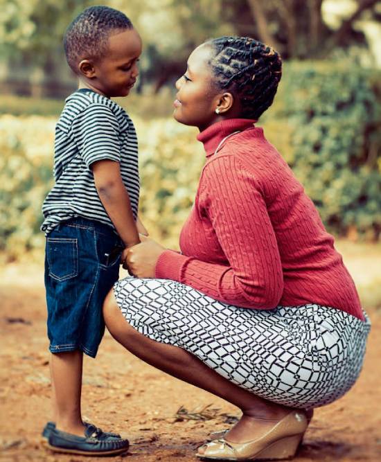 Mother talking to a Son A mother in a red top and a checked skirt squating to talk to a son wearing black and white t-shirt and blue denim short.