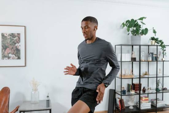 A man in fitness gear doing high jumps in the living room.