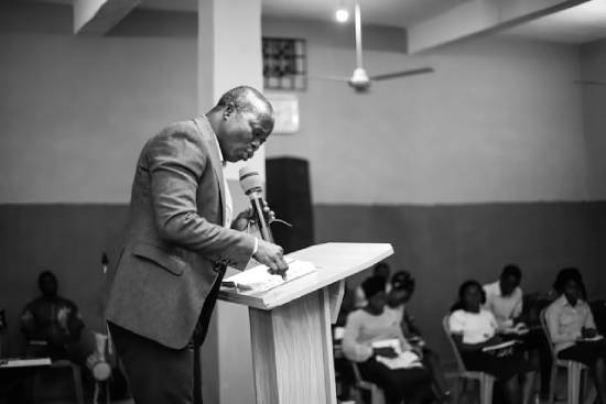 A preacher standing on the podium with an open Bible giving a sermon about fasting.