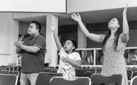 A family attending a prayer meeting and actively participating during the prayers.