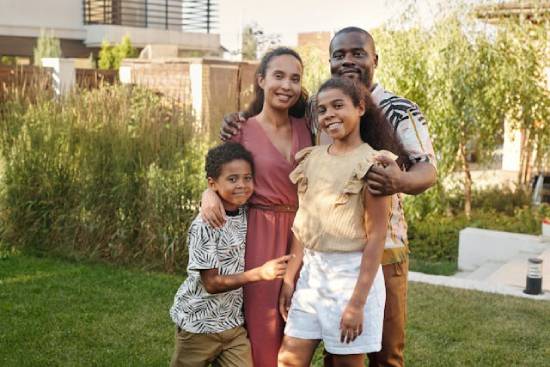 A family of father, mother, and two kids taking a group photo in the garden.