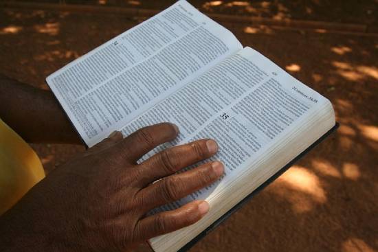 Upclose photo of a person's hands holding an open Bible showing the book of 2 Chronicles.