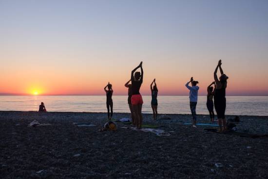 A group of people stretching at the beach during the golden hour.